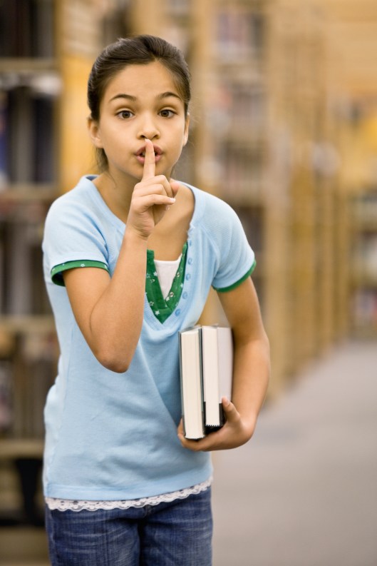 Mixed Race girl shushing in library
