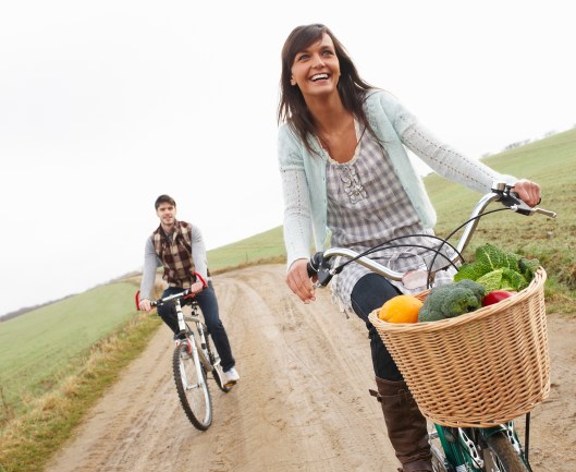 Young couple riding bikes with shopping