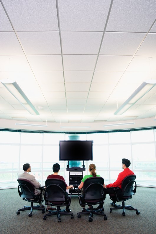 Rear view of group sitting around big screen TV