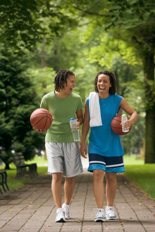 Two teenage girls walking with basketball and water bottles