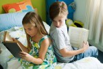 Siblings reading together, boy glancing over shoulder at sister's book