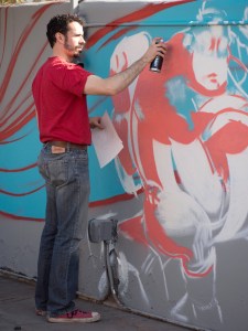 Artist spray painting on a "permission wall" in Tucson, AZ