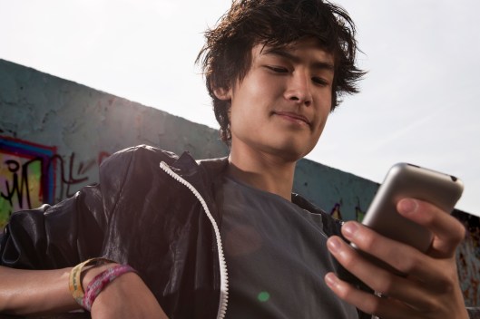 Germany, Berlin, Teenage boy using mobile phone