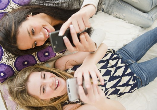 Teenage girls text messaging on cell phones