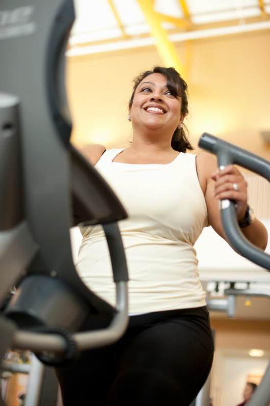Woman using elliptical machine in gym