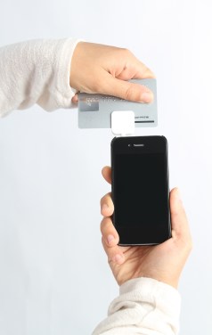 Woman uses a square card reader to make a transaction through her smart phone
