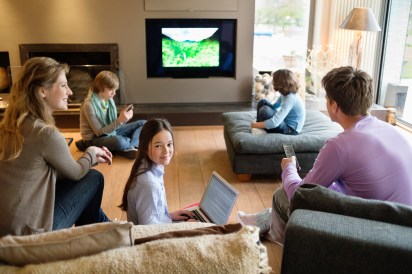 Family using electronic gadgets in a living room