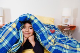 Boy under blanket looking at camera